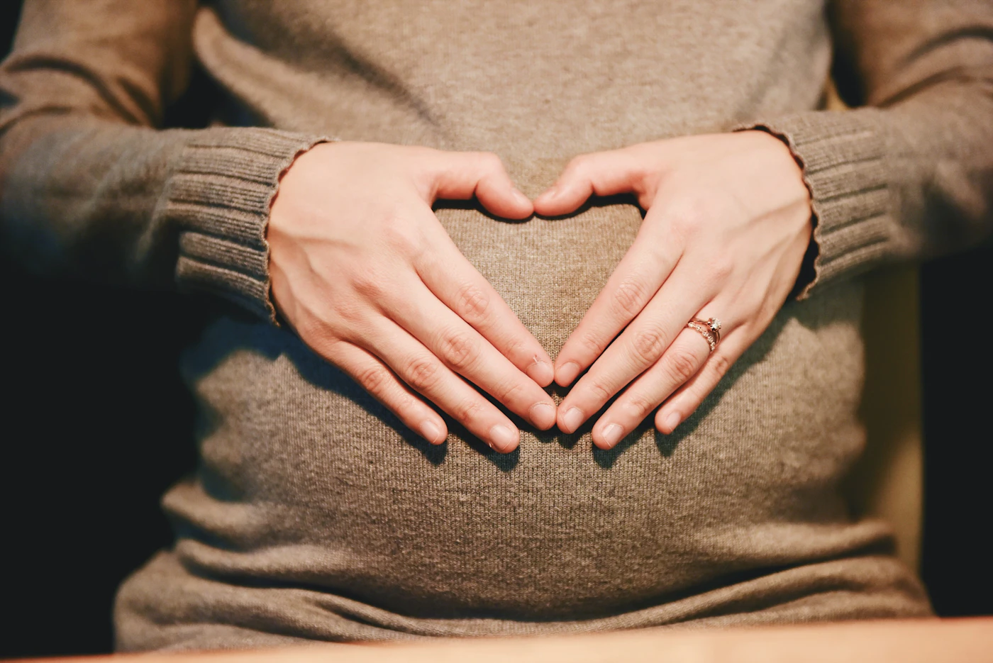 Hands resting gently over a pregnant abdomen